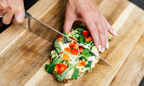 hands cutting into a piece of bread on a cutting board